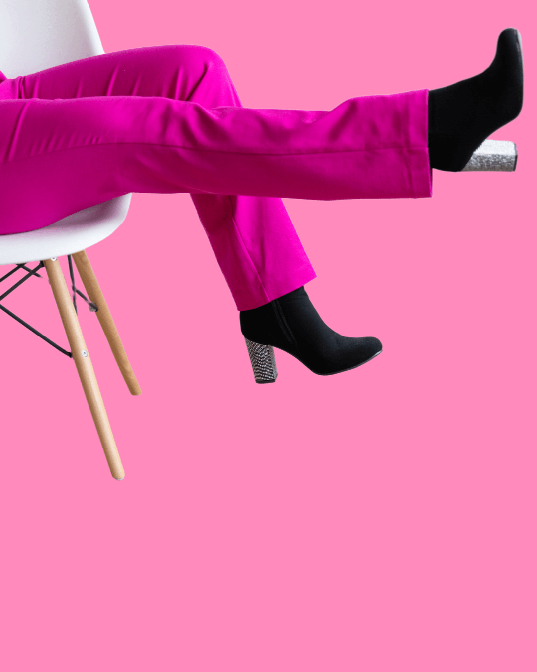 Woman sitting on chair in pink pants and black boots