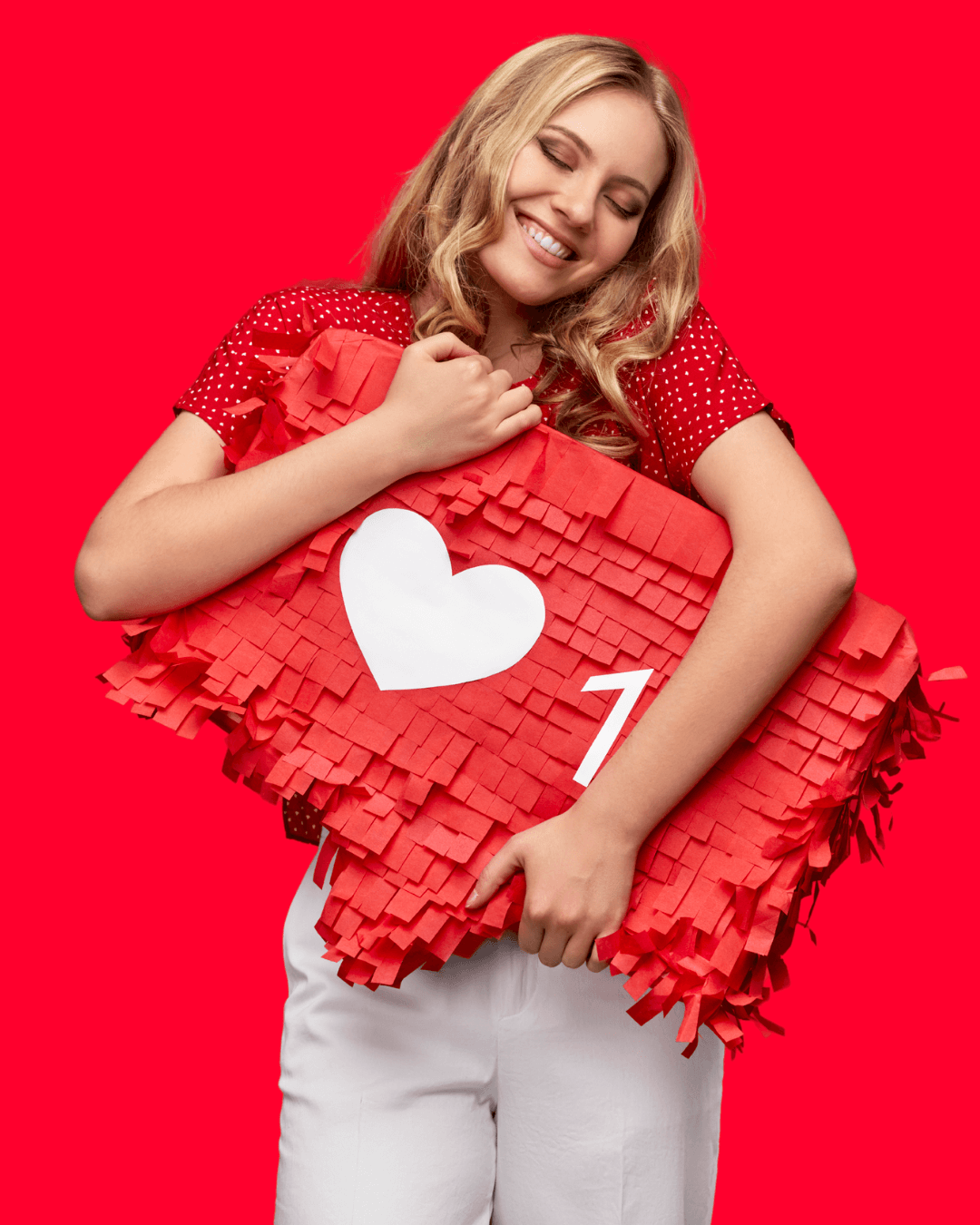 Woman in red shirt and white pants hugging a social heart piñata