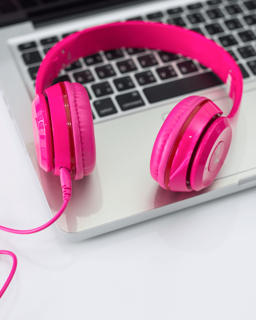 Silver laptop with hot pink headphones