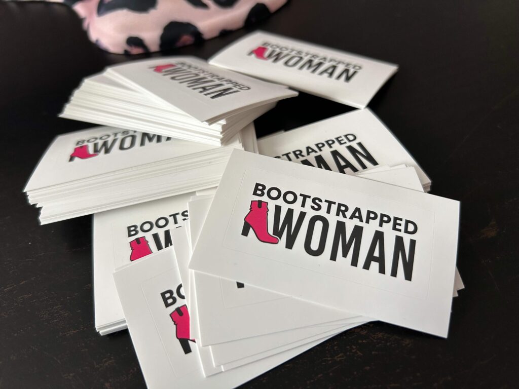 Dozens of Bootstrapped Woman stickers on black desk.